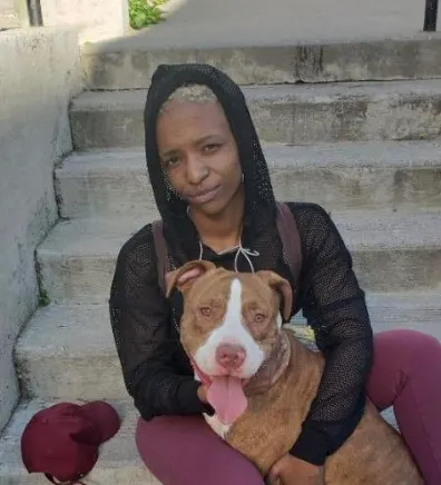 Monique's staff photo from Riverside Animal Hospital South where she is sitting down on some steps holding her tan and white dog.